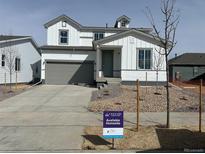 Charming two-story home featuring white siding, a gray garage door, and a well-manicured front yard at 1465 Bloom St, Brighton, CO 80601