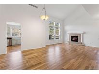 Bright living room boasts a fireplace, hardwood floors, and vaulted ceiling with clerestory windows at 7944 E Lowry Blvd, Denver, CO 80230