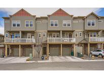 View of townhomes with brick and siding exteriors, individual garages and white balcony railings at 12898 King St, Broomfield, CO 80020