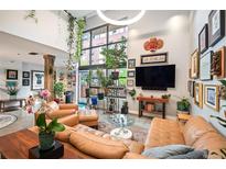 Bright living room featuring large windows, tan leather furniture, modern decor, and vibrant plants at 930 Acoma St # 106, Denver, CO 80204