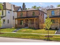 Brick two-story home featuring a welcoming front porch and a beautifully landscaped lawn at 2515 N Gaylord St, Denver, CO 80205