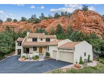 Stunning home with a red tile roof, a three-car garage, and beautifully landscaped yard situated by a majestic red rock formation at 5085 Red Rock Dr, Larkspur, CO 80118
