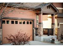 Attached two-car garage featuring a carriage door, stylish brick accents, and an inviting covered entry at 3231 Riverwood Way, Castle Rock, CO 80109