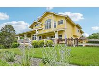 Charming yellow two-story home featuring a welcoming front porch and well-manicured lawn with garden at 9385 Prairie View Dr, Highlands Ranch, CO 80126