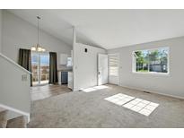 Bright living room features a vaulted ceiling, large window, and access to the kitchen at 17593 E Temple Dr, Aurora, CO 80015