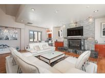 Comfortable living room featuring a stone fireplace and modern white sofas at 180 N Cook St # 509, Denver, CO 80206
