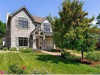 Charming stone-clad two-story home with a well-manicured lawn, mature trees, and beautiful landscaping at 852 Pontiac St, Denver, CO 80220