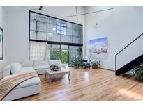 Bright, open living room with soaring ceilings, large windows, and hardwood floors at 3377 Blake St # 205, Denver, CO 80205