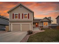 Inviting home with a two-car garage, complemented by a cozy front porch and landscaped front yard at 12028 W Aqueduct Dr, Littleton, CO 80127