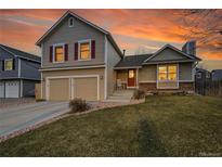 Charming two-story home featuring a two-car garage and a well-manicured front lawn under a beautiful sunset sky at 12028 W Aqueduct Dr, Littleton, CO 80127