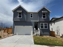 Two-story home featuring gray siding, white trim, and an attached two-car garage at 16947 W 92Nd Dr, Arvada, CO 80007