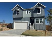 Beautiful two-story home featuring gray siding, white garage door, and charming front entrance under a clear blue sky at 16947 W 92Nd Dr, Arvada, CO 80007