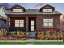 Charming brick home with dormer windows and inviting front porch showcasing manicured landscaping at 5876 Alton St, Denver, CO 80238