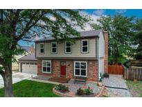Charming two-story home with a red brick facade, manicured lawn, and lush landscaping at 312 Allen St, Golden, CO 80401