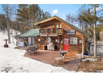 Charming cabin with a large deck, seating area, and beautiful wooded surroundings at 9061 Rex Ln, Conifer, CO 80433