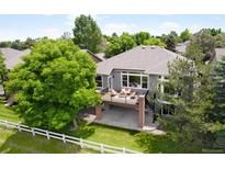 Beautifully landscaped home featuring a spacious deck, spiral staircase, mature trees, and a classic white fence at 1001 Deer Clover Way, Castle Pines, CO 80108