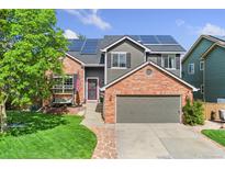 Beautiful two-story home featuring brick and gray siding, solar panels, and a well-manicured front yard at 9821 Bucknell Ct, Highlands Ranch, CO 80129