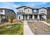 Charming two-story home featuring a covered porch and landscaped front yard, stone accents, and neutral exterior color at 21413 E 59Th Pl, Aurora, CO 80019