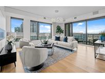 Bright living room featuring hardwood floors, stylish furnishings, large windows with city views and modern lighting at 1750 Wewatta St # 1501, Denver, CO 80202
