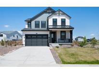 Two-story home boasts a gray and white exterior, attached two-car garage, and a cozy front porch at 1041 W Witherspoon Dr, Elizabeth, CO 80107