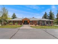Charming brick home featuring a welcoming wood-accented entrance and a well-manicured lawn at 27436 Kennedy Gulch Rd, Conifer, CO 80433