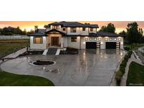 Stunning two-story home with a three-car garage and circular driveway, professionally landscaped at sunset at 2495 Red Hawk Pl, Broomfield, CO 80023