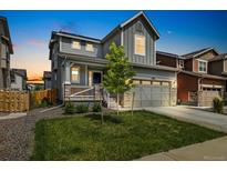 Charming two-story home with a manicured lawn, gray siding, and a welcoming front porch at 10983 Uvalda St, Commerce City, CO 80022