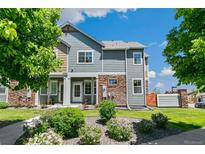 Inviting townhome showcasing stone accents, lush landscaping, and a charming covered entrance, bathed in natural light at 12860 Jasmine St # C, Thornton, CO 80602