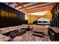 Inviting rooftop deck featuring a hot tub, comfortable seating, and a stylish fire pit beneath string lights at dusk at 3030 Wilson Ct # 5, Denver, CO 80205