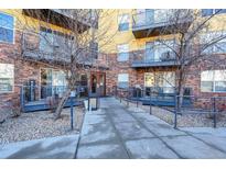 Low-rise brick apartment building exterior featuring covered entry with access ramp, walkways, and metal balconies at 9019 E Panorama Cir # D416, Englewood, CO 80112