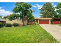Charming brick home features a well-manicured lawn, mature trees, and a two-car garage with a red door at 1705 Lewis St, Lakewood, CO 80215