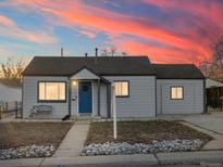 Charming single-story home featuring a well-maintained lawn, inviting blue door, and pleasant curb appeal set under a colorful sunset at 1385 S Newton St, Denver, CO 80219