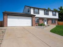 Two-story home featuring brick and siding with a two car garage and a concrete driveway and walkway at 9451 W Hialeah Pl, Littleton, CO 80123