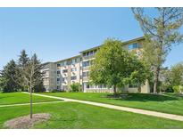 Spacious lawn and sidewalk leading to the well-maintained building under a blue sky with mature trees at 705 S Alton Way # 4D, Denver, CO 80247
