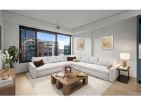 Bright living room boasts a large window, modern decor, and a comfortable, oversized white couch at 1750 Wewatta St # 1227, Denver, CO 80202