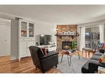 Cozy living room featuring a stone fireplace, wood floors, and built-in shelving at 8555 Fairmount Dr # G208, Denver, CO 80247