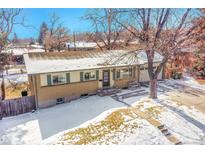 Charming ranch-style home featuring a brick facade, green shutters, and a well-maintained front yard covered in light snow at 12286 W Tennessee Ave, Lakewood, CO 80228
