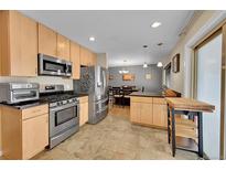 Well-lit kitchen featuring stainless steel appliances, wood cabinets, and an attached dining area at 12286 W Tennessee Ave, Lakewood, CO 80228