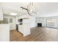 Inviting living room with a fireplace, adjacent to a modern kitchen with sleek, white cabinets at 18302 E Kepner Pl # 207, Aurora, CO 80017
