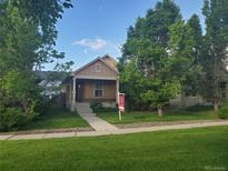 Charming home with a well-maintained front yard, mature trees, and inviting porch at 23317 E Saratoga Cir, Aurora, CO 80016