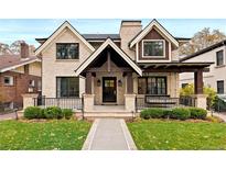 Stunning two-story home boasts a brick facade, covered porch, black trim windows, and beautiful landscaping at 2218 S Clayton St, Denver, CO 80210
