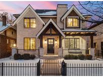Charming two-story home with a brick facade, black trim windows, a front porch swing, and a wrought iron fence at 2218 S Clayton St, Denver, CO 80210