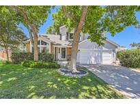 Charming two-story home featuring a manicured lawn, mature trees, and a two-car garage at 9492 Crestmore Way, Highlands Ranch, CO 80126