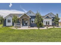 Inviting blue two-story home with a well-manicured lawn and stone entryway at 41975 Muirfield Loop, Elizabeth, CO 80107
