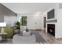 Virtually staged living room with fireplace and wood-look floors at 1830 Newland Ct # 106, Lakewood, CO 80214