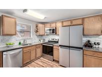 Well-lit kitchen features wood cabinets, stainless steel appliances and granite countertops at 5833 S Pearl St, Centennial, CO 80121
