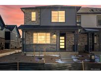 Two-story home with stone and gray siding, front porch, and landscaping at 20972 E 66Th Ave, Aurora, CO 80019