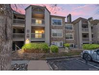 Condo exterior featuring stone accents, balconies, and manicured landscaping at 9222 E Arbor Cir # L, Englewood, CO 80111