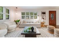 Bright living room with hardwood floors, gray sofa, white armchair, and large window with natural light at 2090 Irving St, Denver, CO 80211
