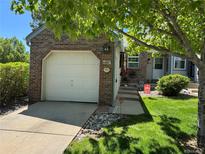 Charming brick home featuring a well-manicured lawn and attached one-car garage at 6887 S Dover Way, Littleton, CO 80128